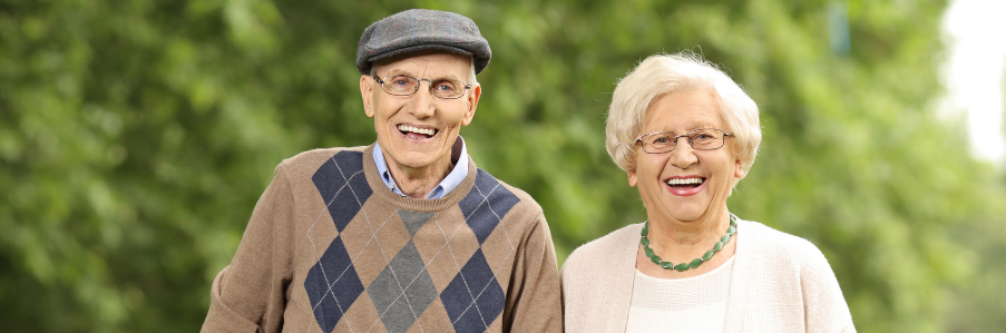 Pareja de adultos mayores sonríen alegremente mientras disfrutan de un paseo al aire libre