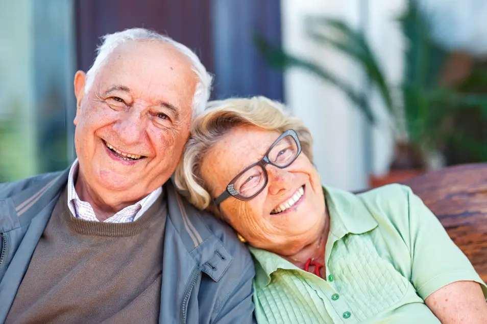 Pareja de residentes adultos mayores sonríen felices, reflejando los valores de compañerismo de El Roble Residencia